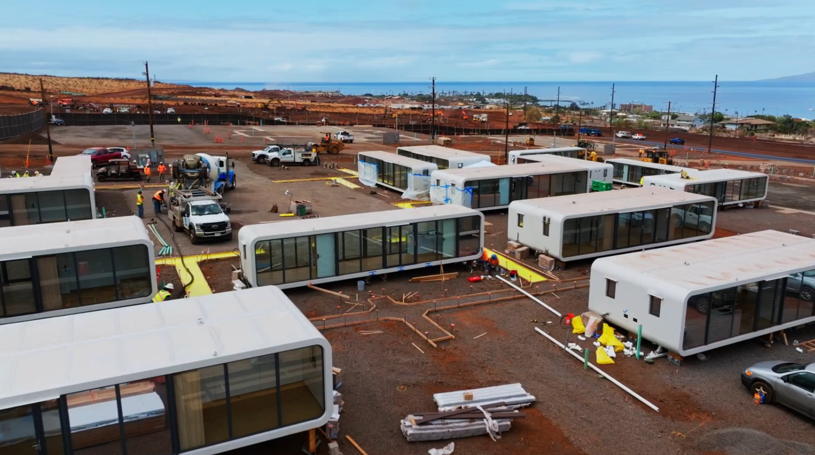 Maui disaster-relief housing — aerial view of dozens of modular homes being installed on site with the Lahaina coastline behind